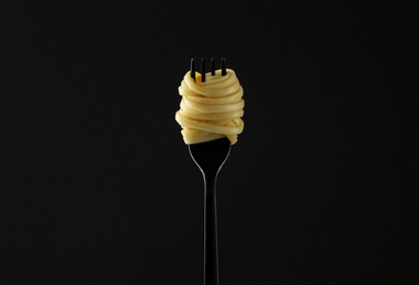 Photo of Fork with tasty pasta on black background