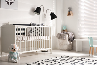 Photo of Cute baby room interior with crib and decor elements