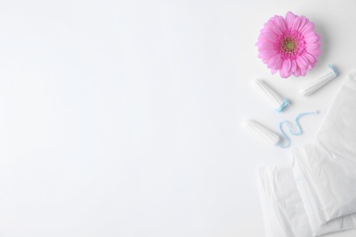 Different feminine hygiene products and flower on white background, top view with space for text. Gynecological care