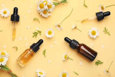 Photo of Flat lay composition with chamomile flowers and cosmetic bottles of essential oil on color background