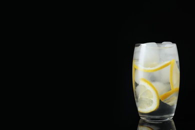 Photo of Glass of cocktail with vodka, ice and lemon on black background. Space for text