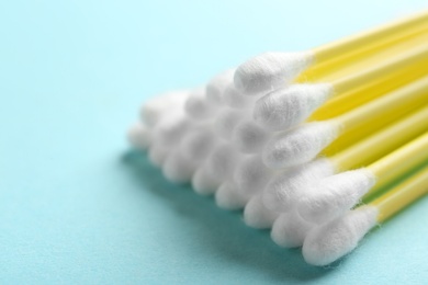 Pile of cotton swabs on color background, closeup. Space for text