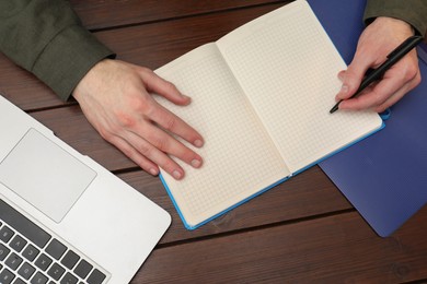 Photo of Man taking notes at wooden table, top view