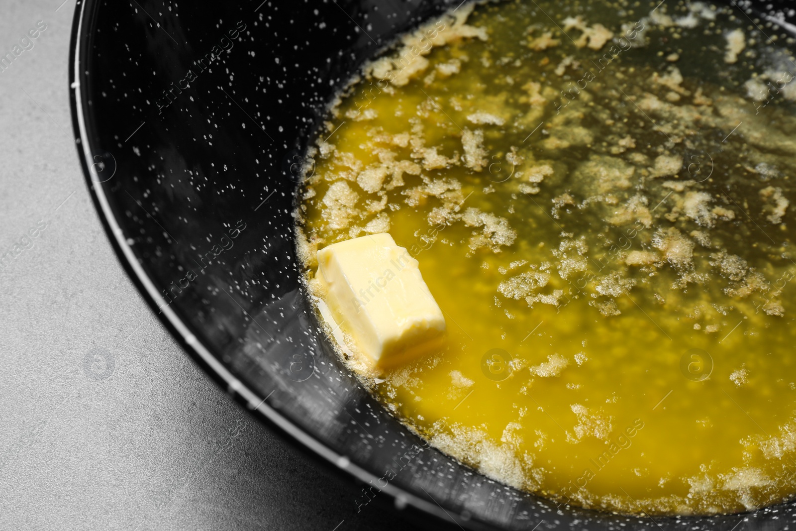 Photo of Frying pan with melting butter on table, closeup