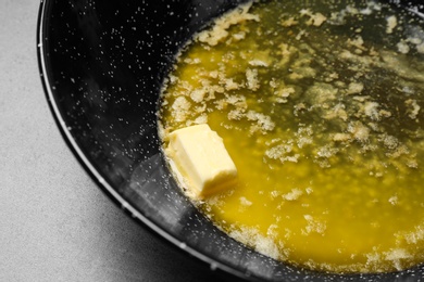 Frying pan with melting butter on table, closeup