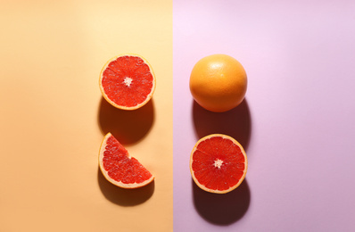 Cut and whole ripe grapefruits on color background, flat lay