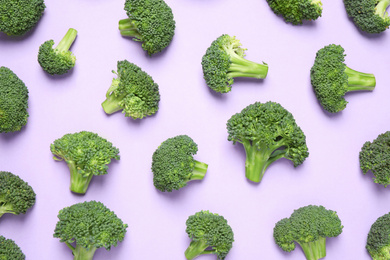 Photo of Fresh tasty broccoli on violet background, flat lay