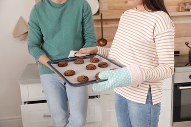 Photo of Young couple with tray of oven baked cookies in kitchen, closeup