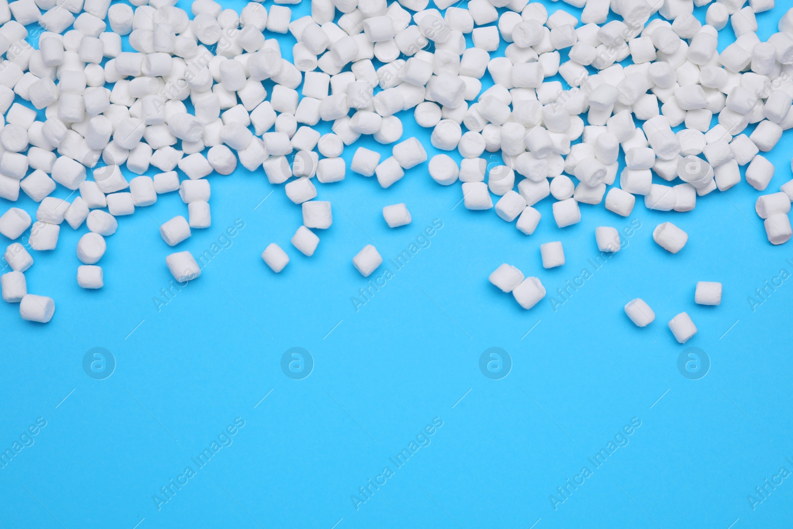 Photo of Delicious sweet marshmallows on light blue background, flat lay. Space for text