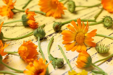 Photo of Beautiful calendula flowers on yellow wooden table, closeup