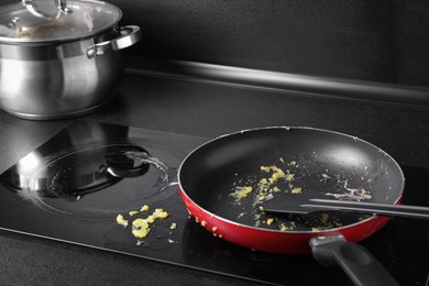 Dirty frying pan with spatula on cooktop in kitchen