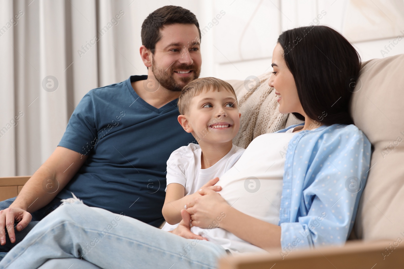 Photo of Pregnant woman spending time with her son and husband at home. Happy family