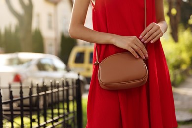 Photo of Woman with stylish bag in red dress outdoors, closeup