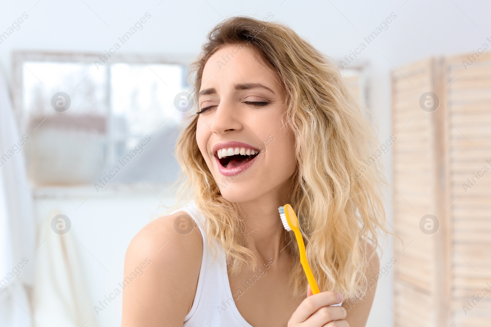 Photo of Young woman brushing her teeth in bathroom