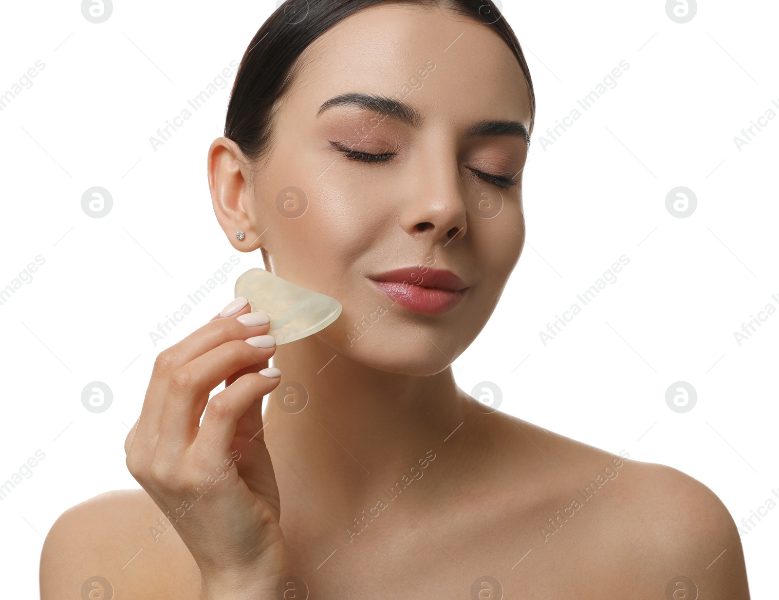 Photo of Beautiful young woman doing facial massage with gua sha tool on white background, closeup