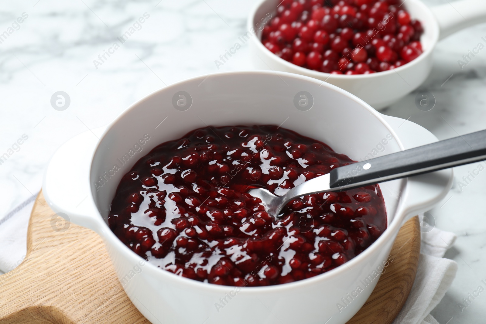 Photo of Fresh cranberry sauce in bowl served on white table, closeup