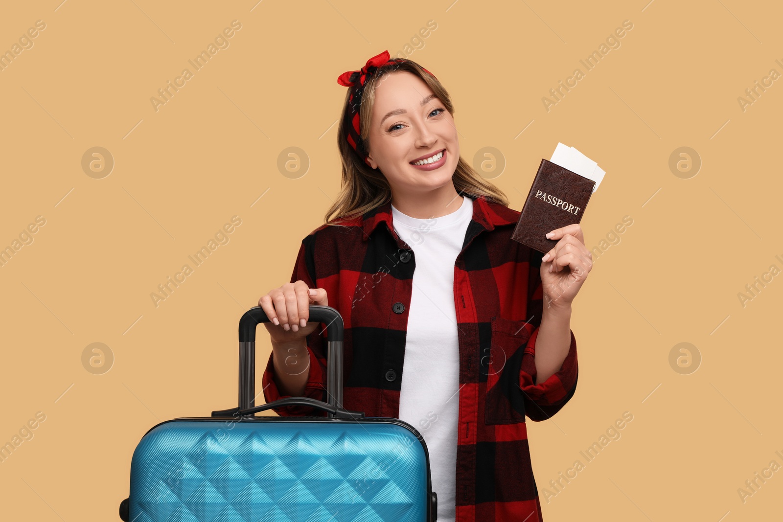 Photo of Happy young woman with passport, ticket and suitcase on beige background