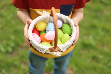 Easter celebration. Little boy holding basket with painted eggs outdoors, closeup