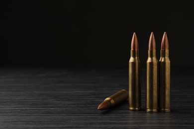 Photo of Many bullets on black wooden table. Space for text