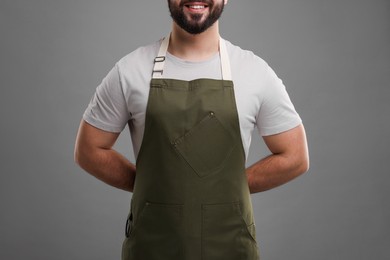 Photo of Smiling man in kitchen apron on grey background, closeup. Mockup for design