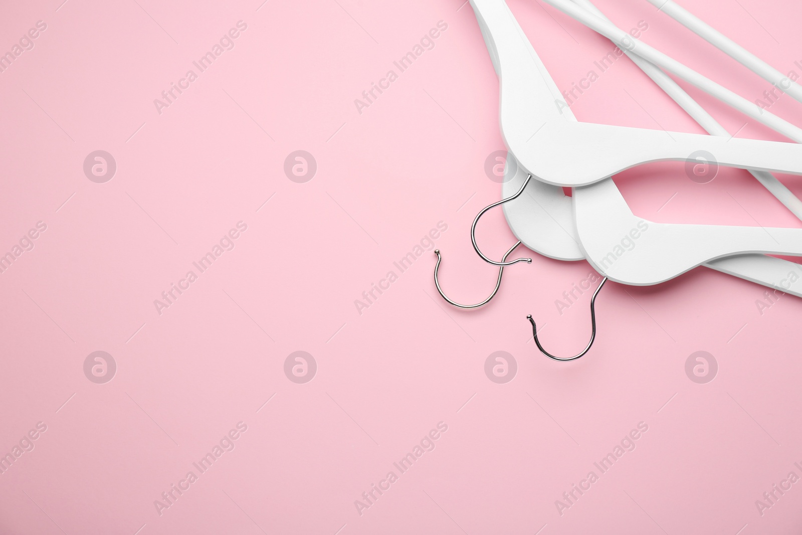 Photo of White hangers on pink background, top view. Space for text