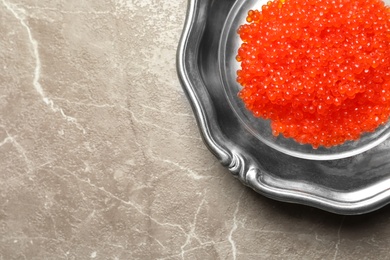 Dish with delicious red caviar on color background