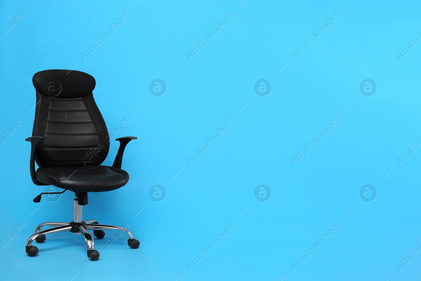 Photo of Comfortable office chair on light blue background, space for text