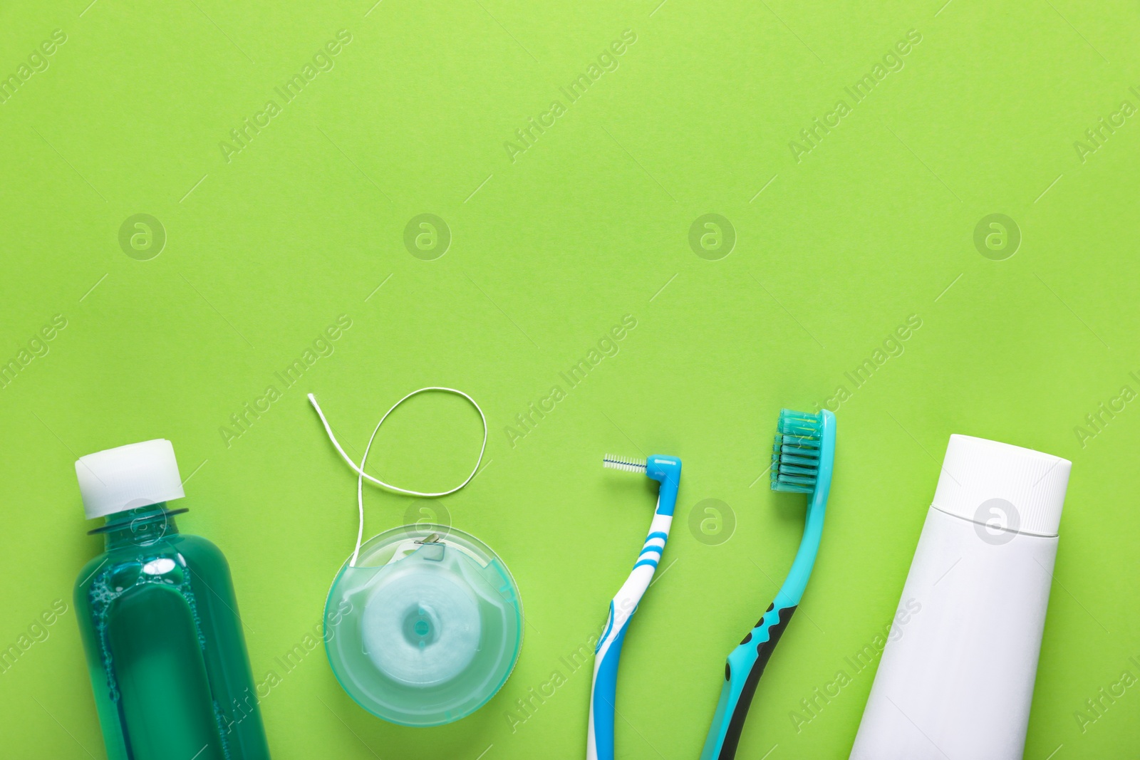 Photo of Flat lay composition with dental floss and different teeth care products on green background, space for text