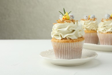 Photo of Tasty Easter cupcakes with vanilla cream on white table, space for text