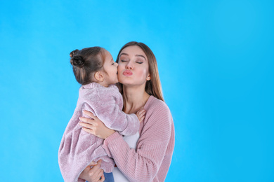 Young mother and little daughter on blue background