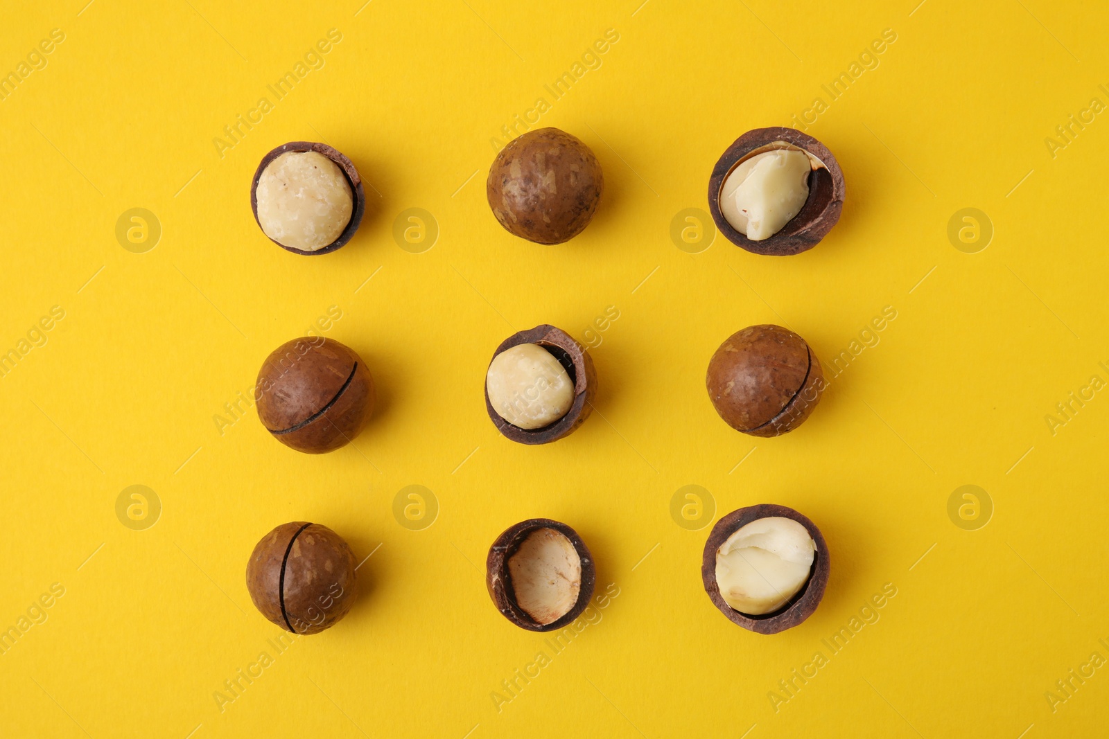 Photo of Tasty Macadamia nuts on yellow background, flat lay
