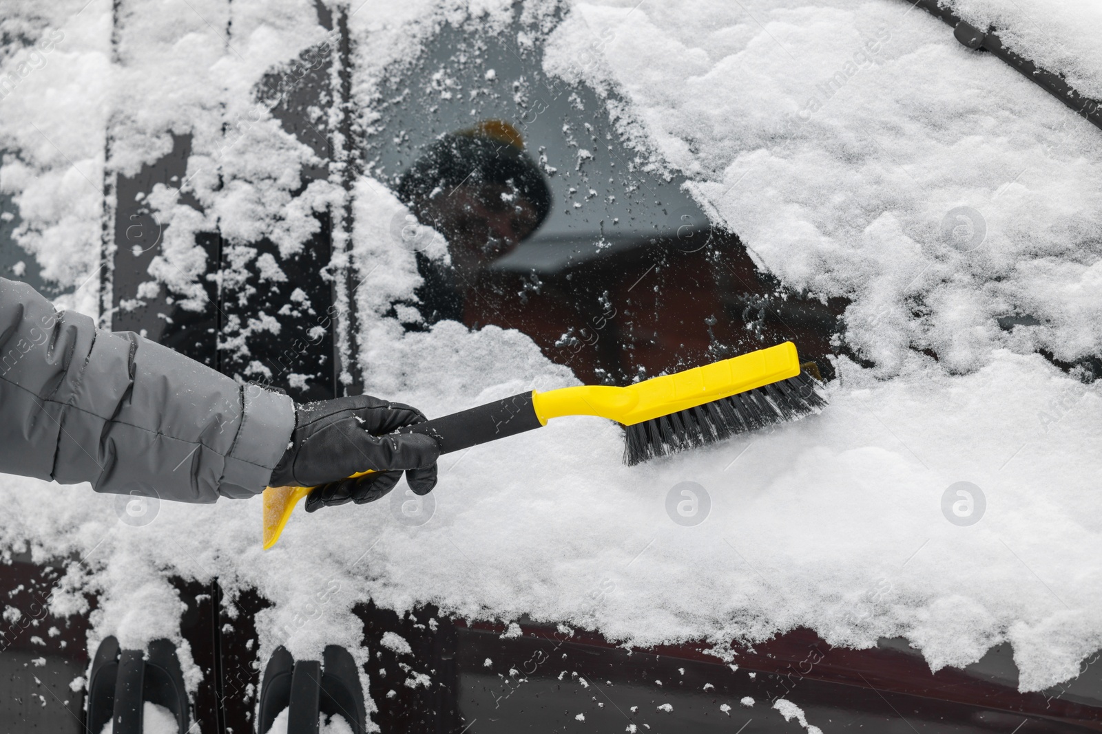 Photo of Man cleaning snow from car window outdoors, closeup