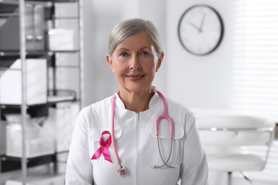 Photo of Doctor with stethoscope and pink ribbon indoors. Breast cancer awareness