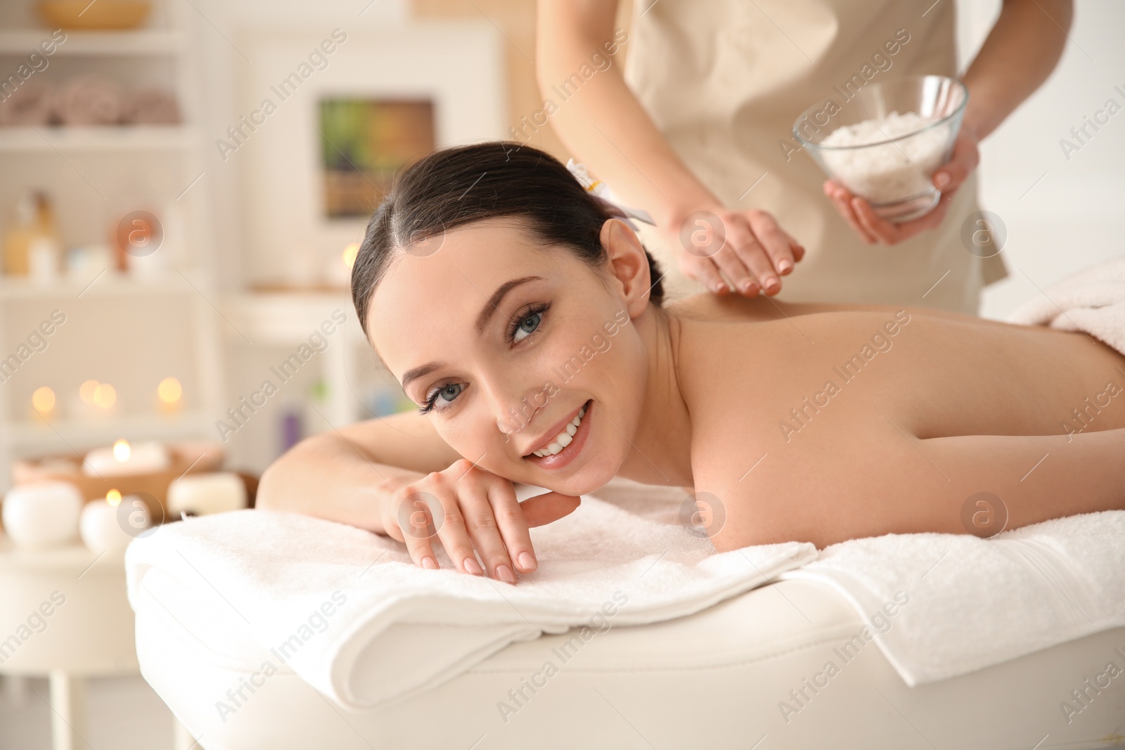 Photo of Beautiful young woman having massage with body scrub in spa salon