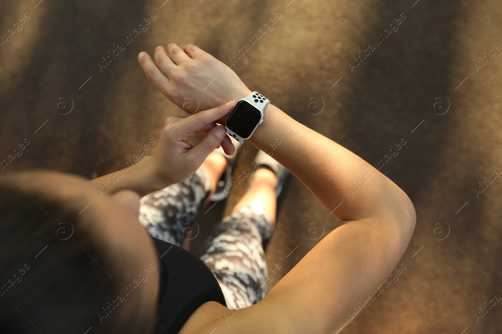 Photo of Woman using modern smart watch during training outdoors, top view