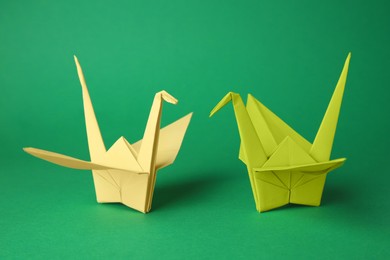 Colorful paper origami cranes on green background