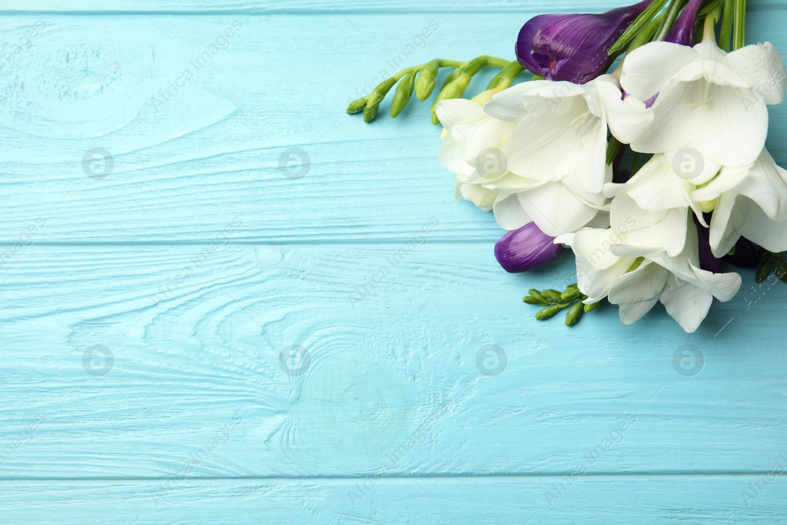 Photo of Bouquet of beautiful spring flowers on blue wooden table, top view. Space for text