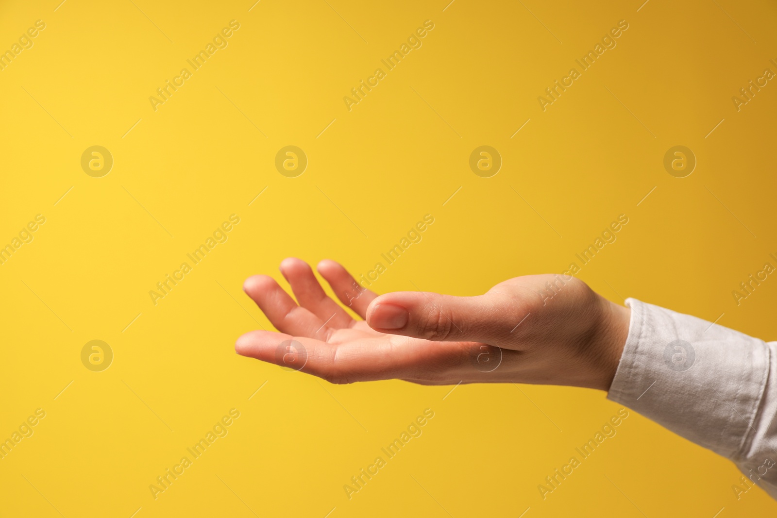 Photo of Woman holding something in hand on yellow background, closeup. Space for text