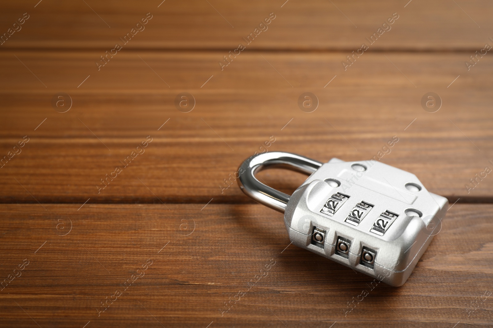 Photo of Modern combination lock on wooden table. Space for text