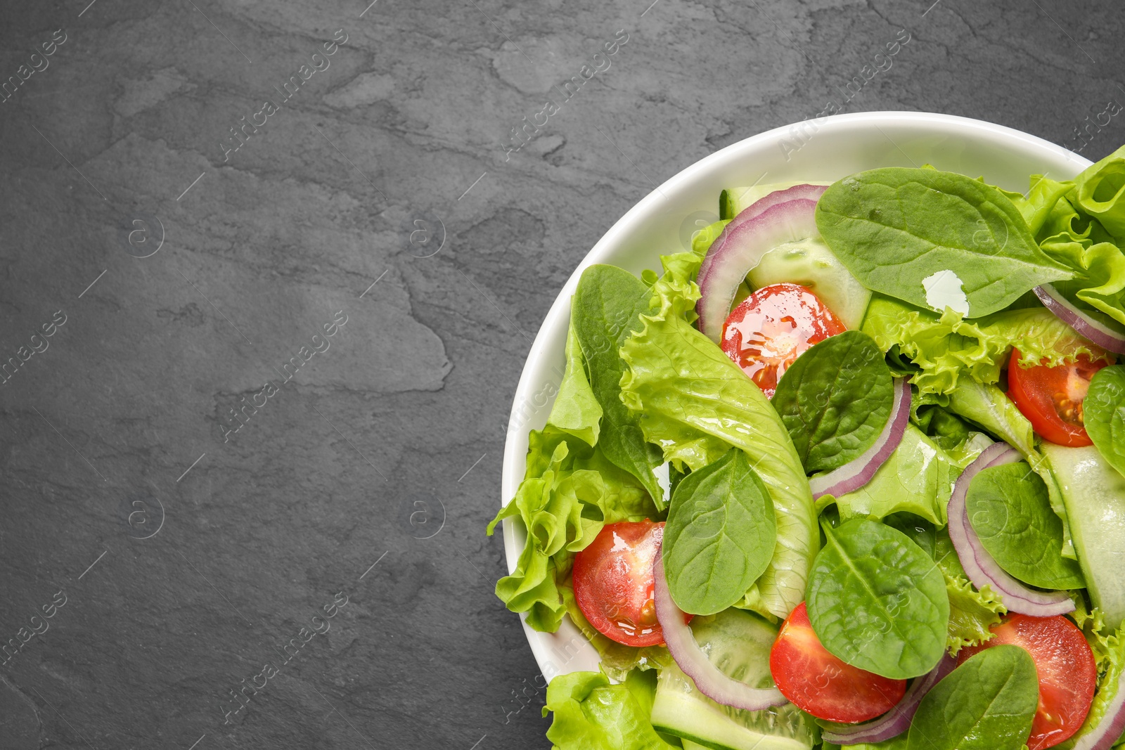 Photo of Delicious vegetable salad on grey table, top view. Space for text