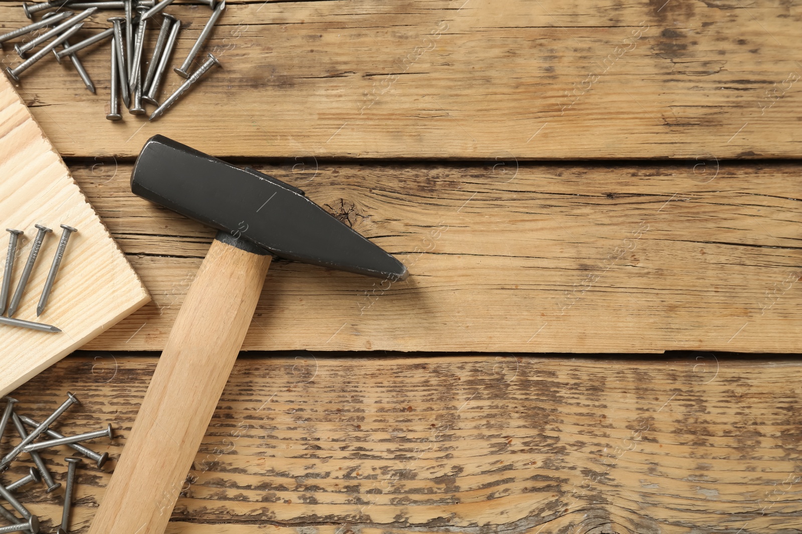 Photo of Hammer and metal nails on wooden table, flat lay. Space for text