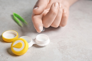 Photo of Woman holding contact lens over table, closeup