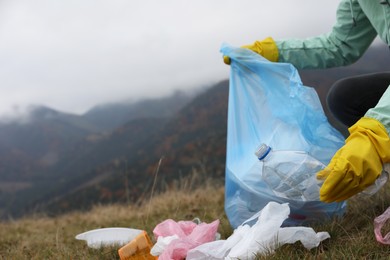 Photo of Woman with trash bag collecting garbage in nature, closeup. Space for text