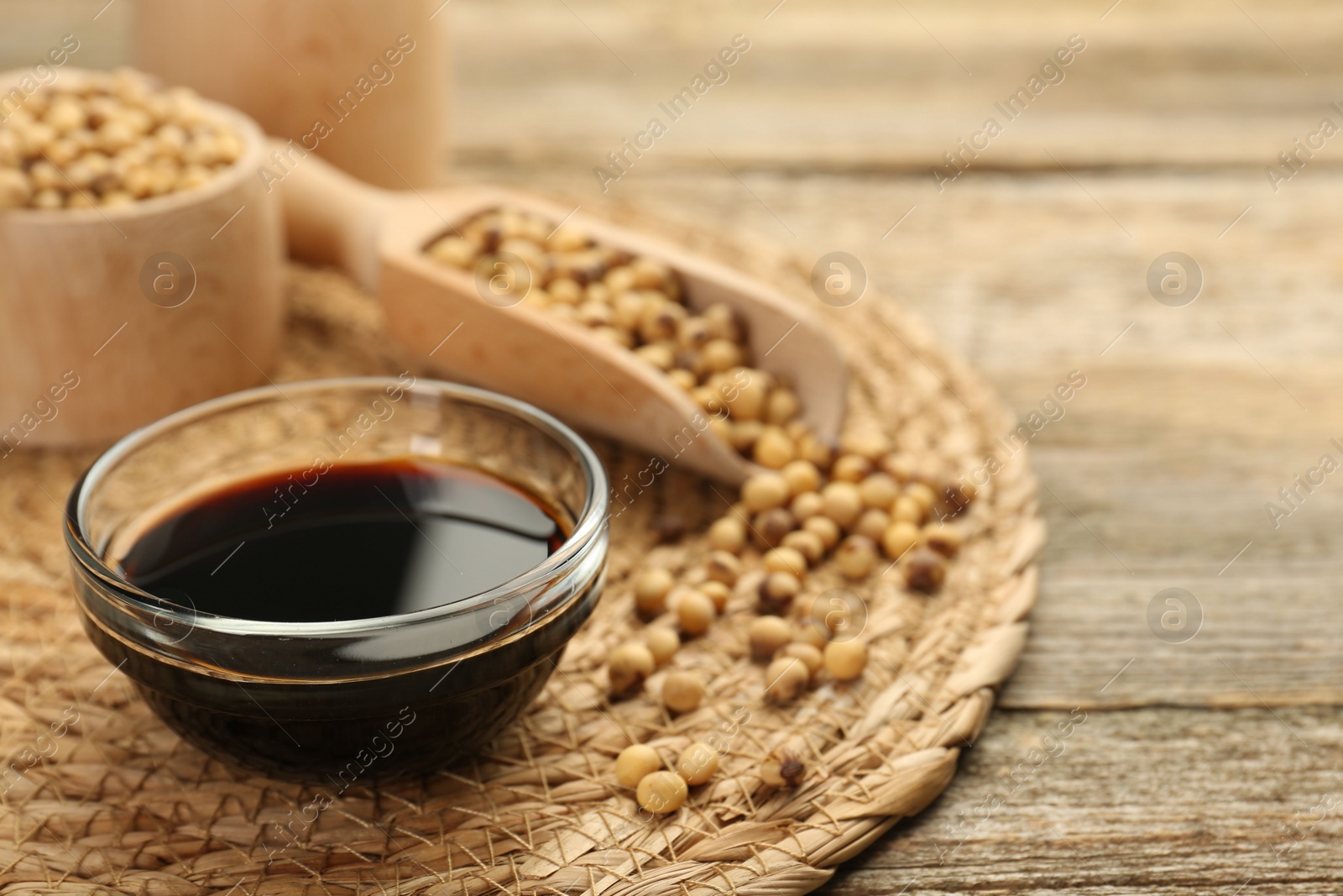 Photo of Soy sauce in bowl and beans on wooden table. Space for text