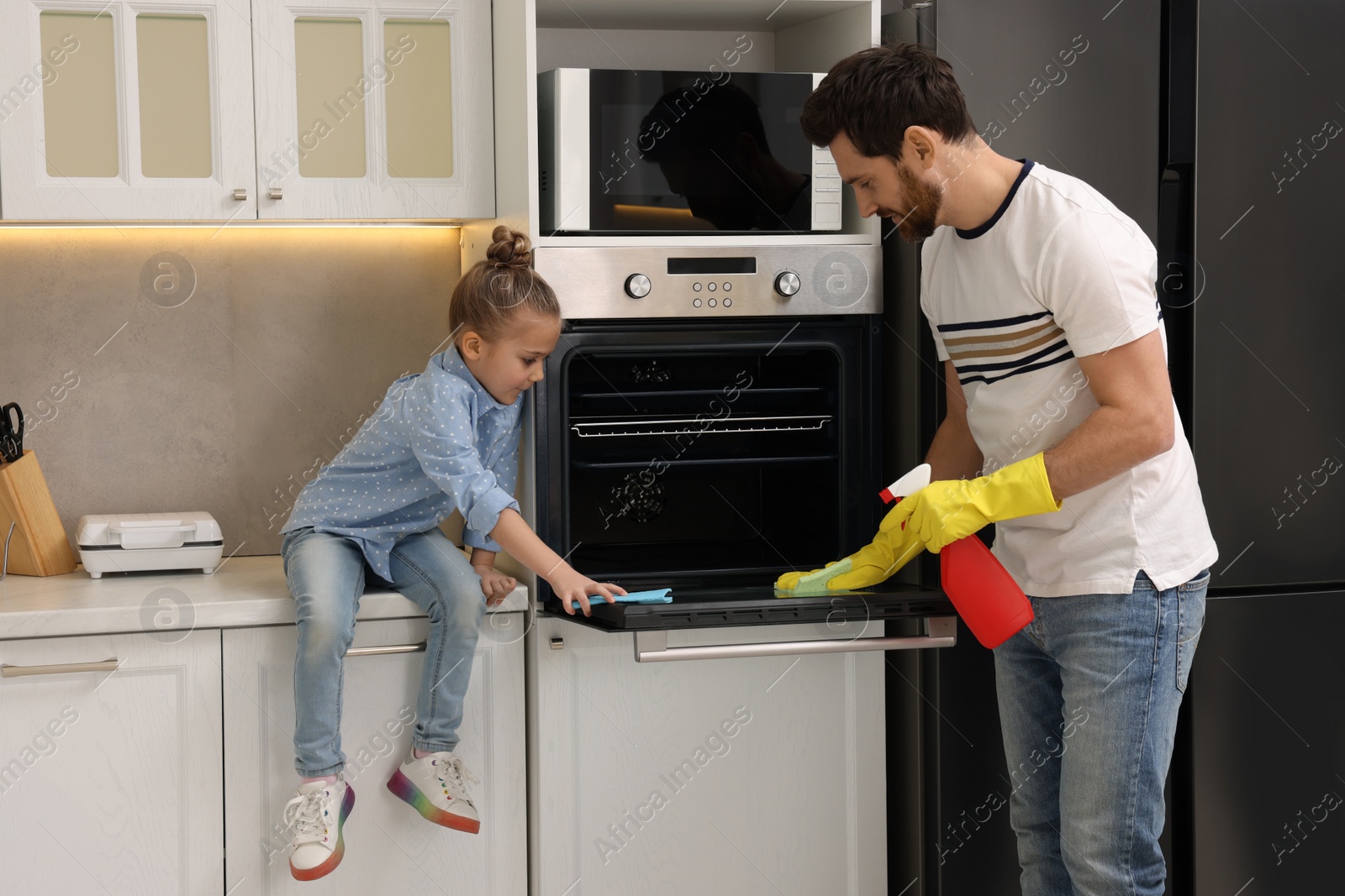 Photo of Spring cleaning. Father and daughter tidying up oven in kitchen together