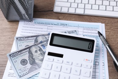 Photo of Tax accounting. Calculator, document, dollar banknotes and pen on table, closeup