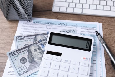 Tax accounting. Calculator, document, dollar banknotes and pen on table, closeup