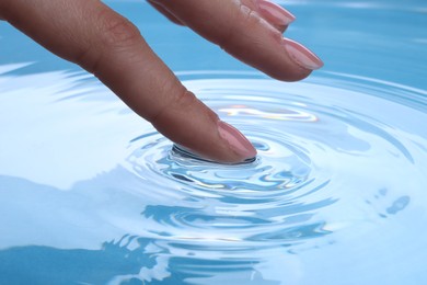 Woman touching clear water, closeup. Making ripples