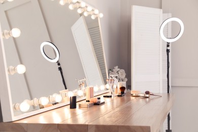 Photo of Modern mirror with light bulbs on dressing table in makeup room