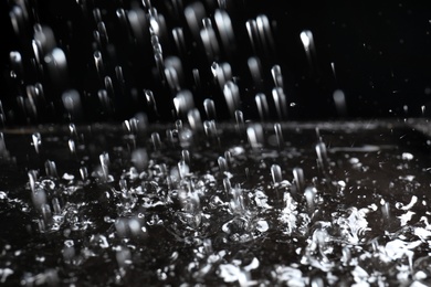 Photo of Heavy rain falling down on ground against dark background, closeup